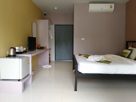 Habitación de hotel con una cama, un escritorio con hervidor, televisión y armario.