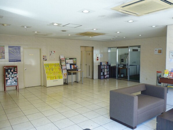 A reception area with a reception desk, a seating area, and a wall with informational posters. - Smile Hotel Mito (Mito)