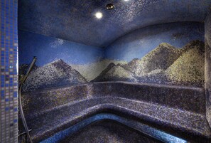 Una habitación con un muro de mosaico que representa un paisaje montañoso.