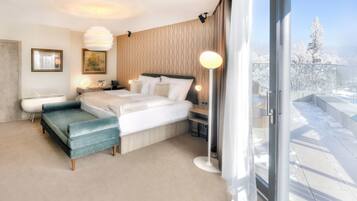 Une chambre d’hôtel moderne équipée d’un lit, d’une banquette, d’une table de chevet et d’une grande fenêtre donnant sur la ville.