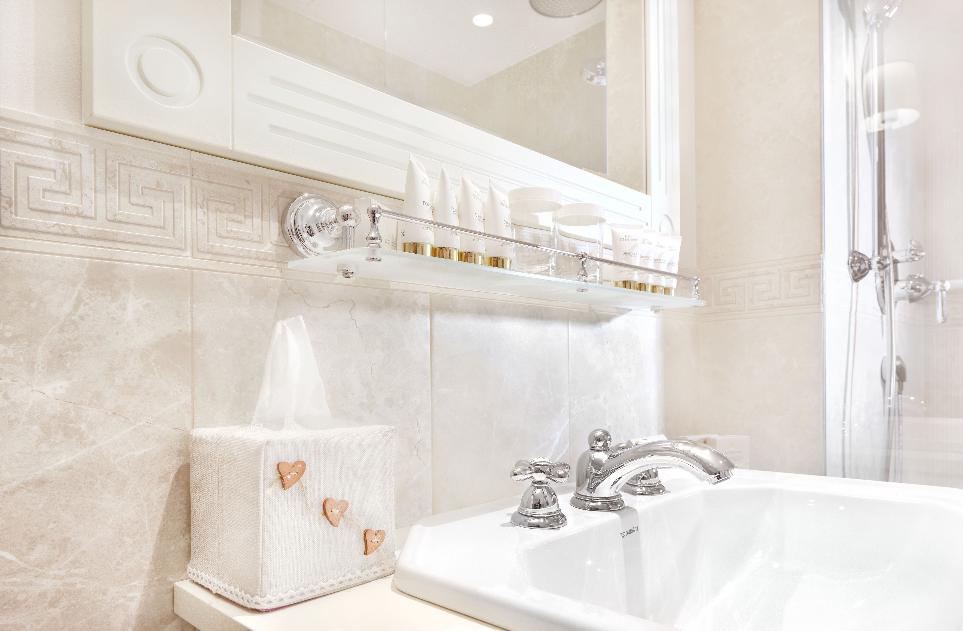 A bathroom with a large mirror, a bathtub, and a shelf with toiletries.