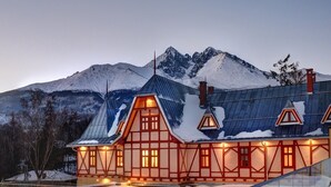 A chalet-style building with a steeply pitched roof, wooden framing, and a snow-covered mountain backdrop.