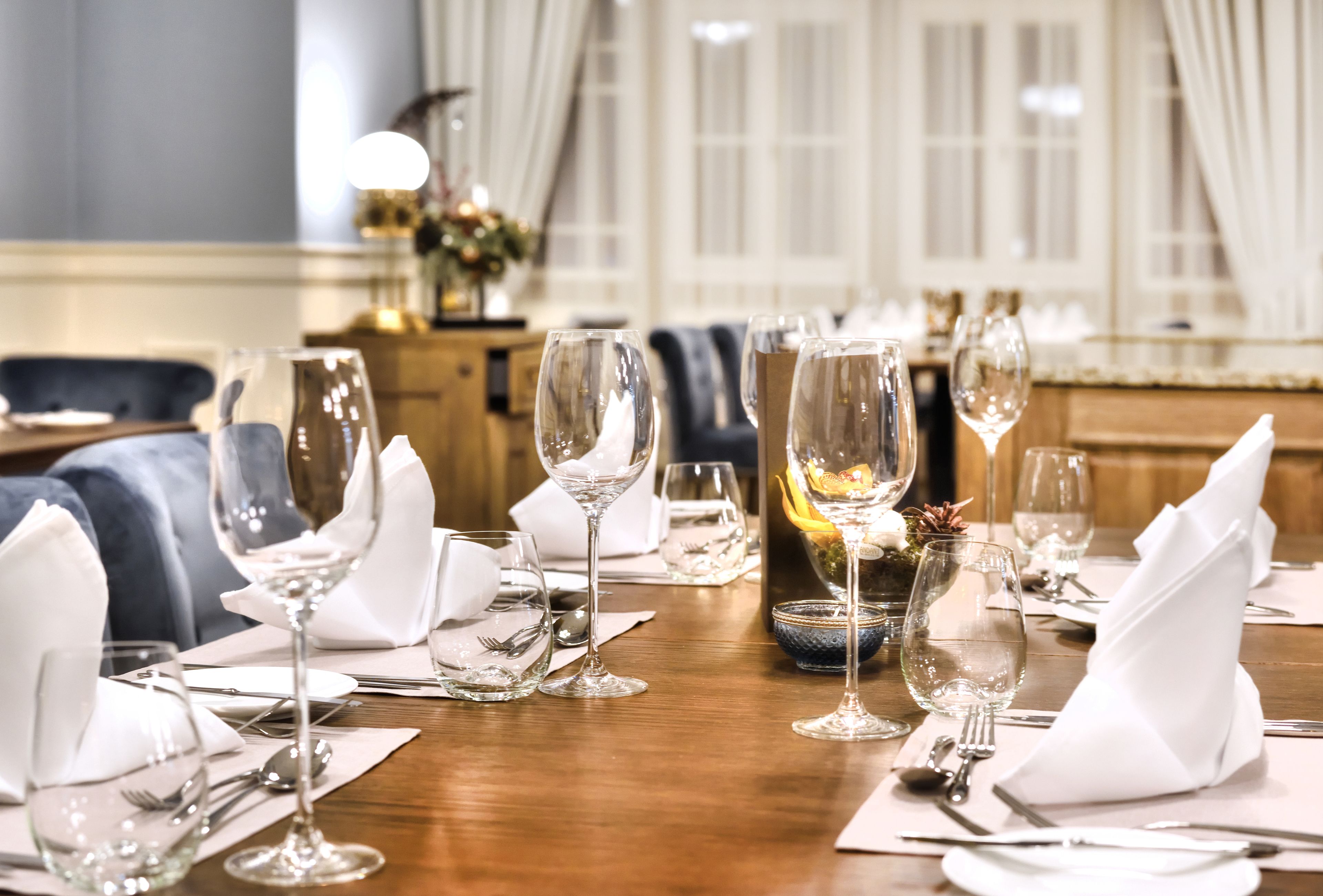 A dining table set with multiple wine glasses, plates, and cutlery, indicating a formal dining arrangement.