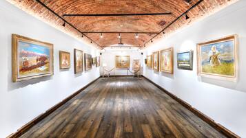 A gallery with paintings on the walls and a wooden floor.
