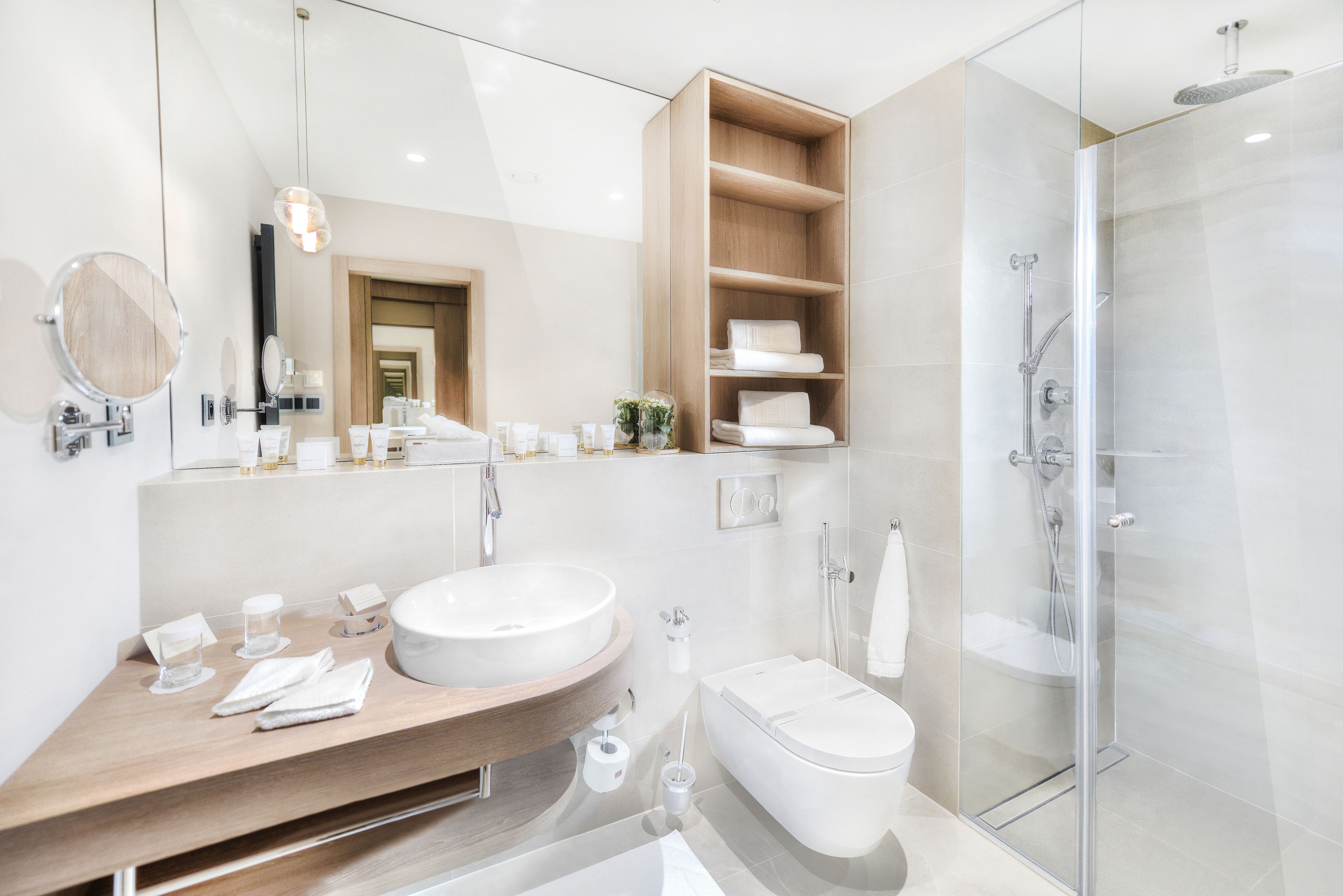 A modern bathroom with a large sink, mirror, and glass shower enclosure.