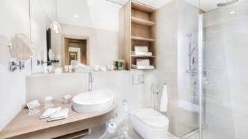 A modern bathroom with a large sink, mirror, and glass shower enclosure.