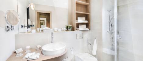 A modern bathroom with a large sink, mirror, and glass shower enclosure.