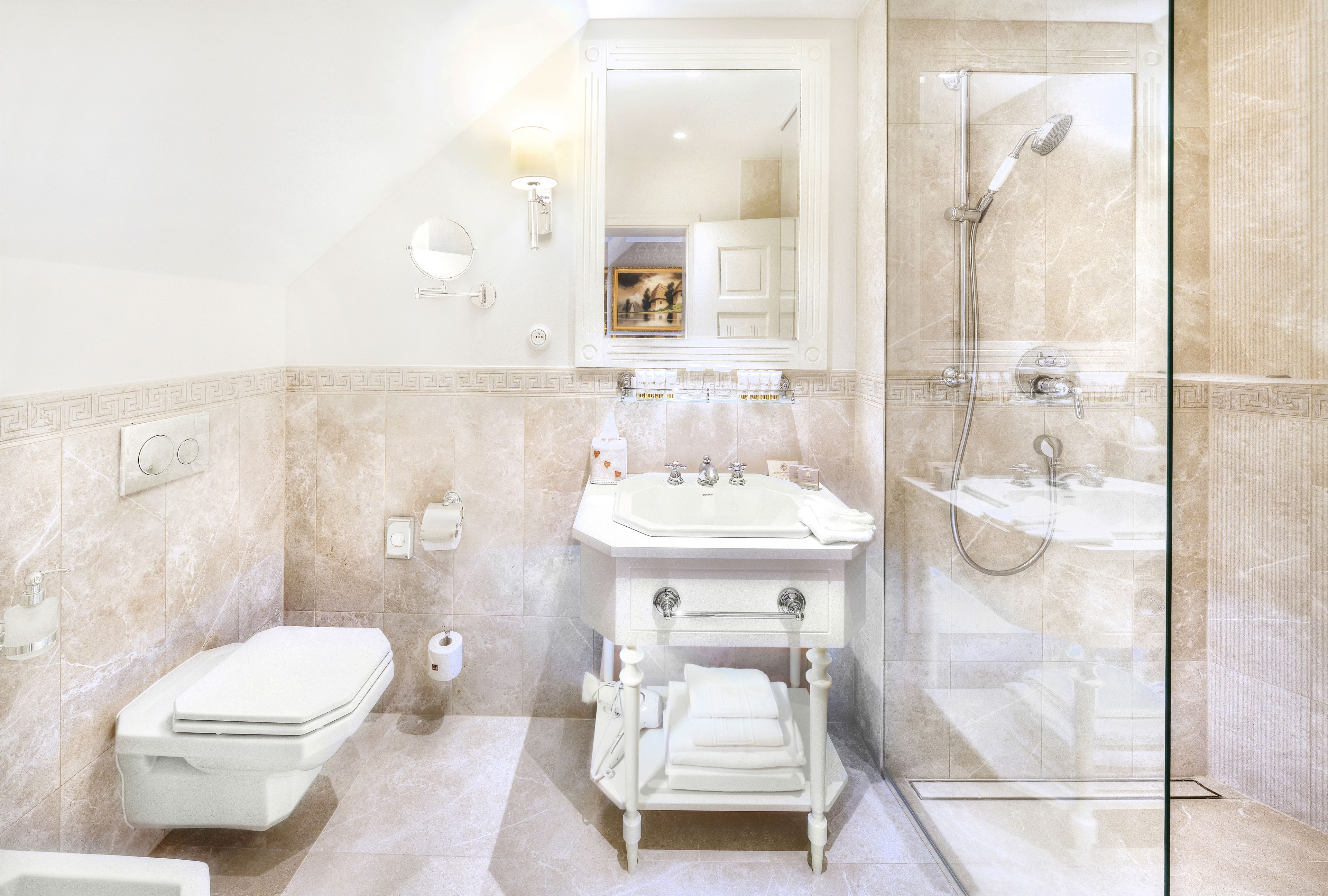 Un baño moderno con ducha de vidrio, lavamanos pedestal y retrete.