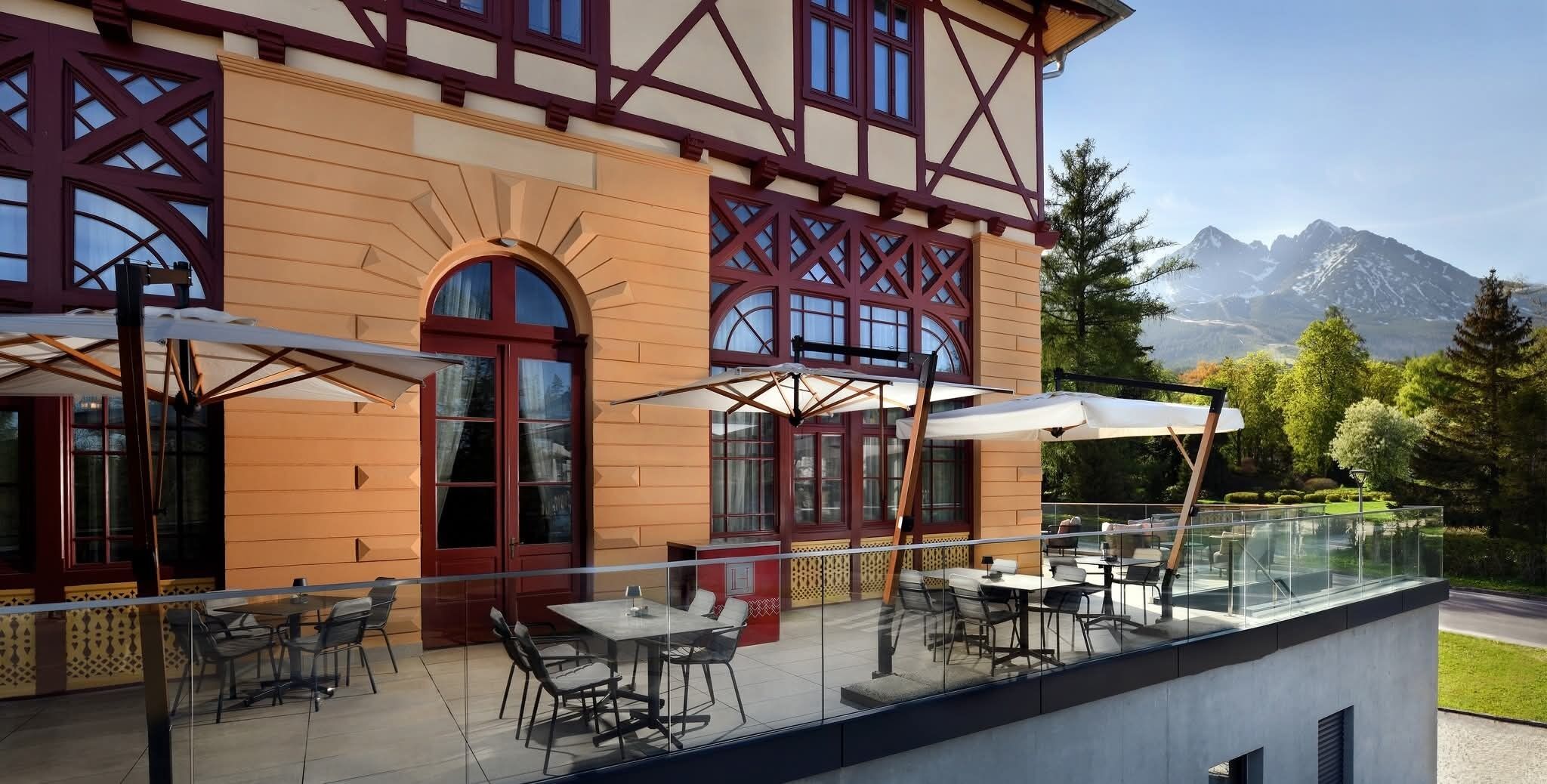 Ein Gebäude mit Balkon, Sitzgelegenheiten im Freien und Blick auf Berge.