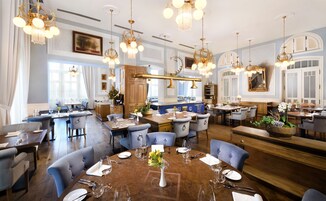 Un comedor amplio con varias mesas, candelabros elegantes y una isla central con un florero.