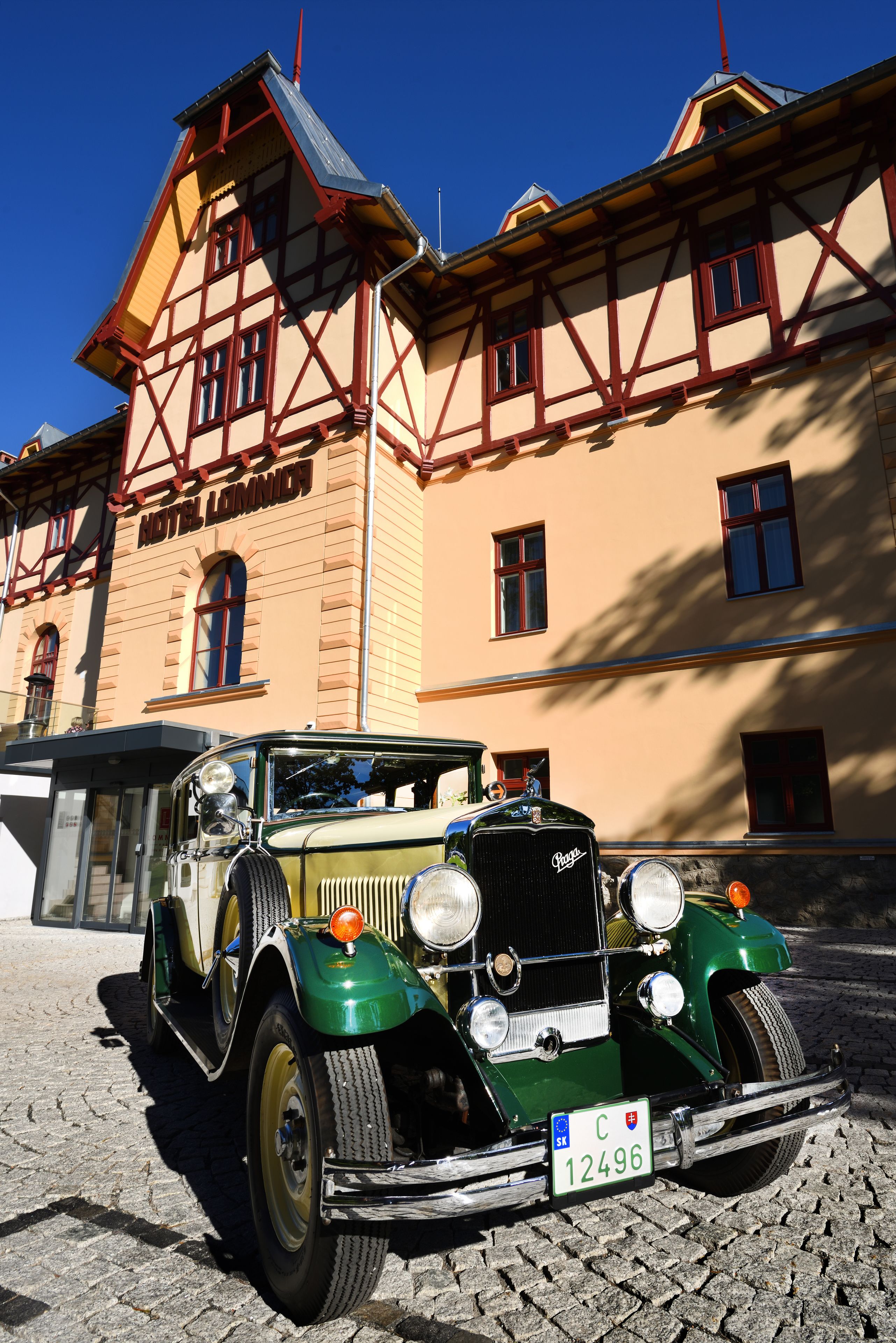 A vintage green car parked in front of a building with a sign reading "Motel Lommich".