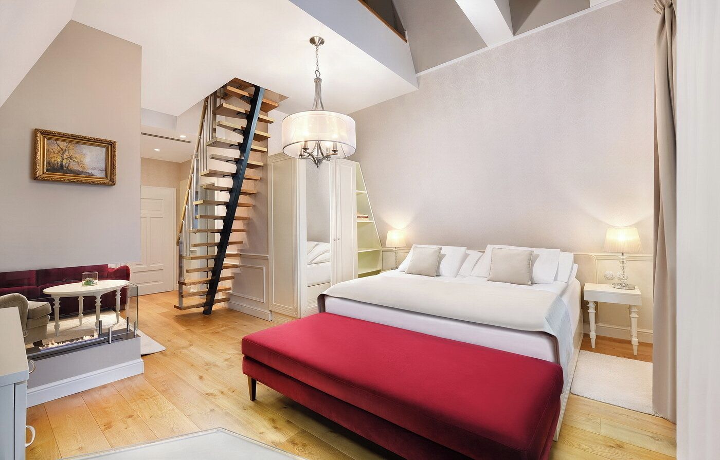 A bedroom with a bed, a red bench, a staircase, and a chandelier.