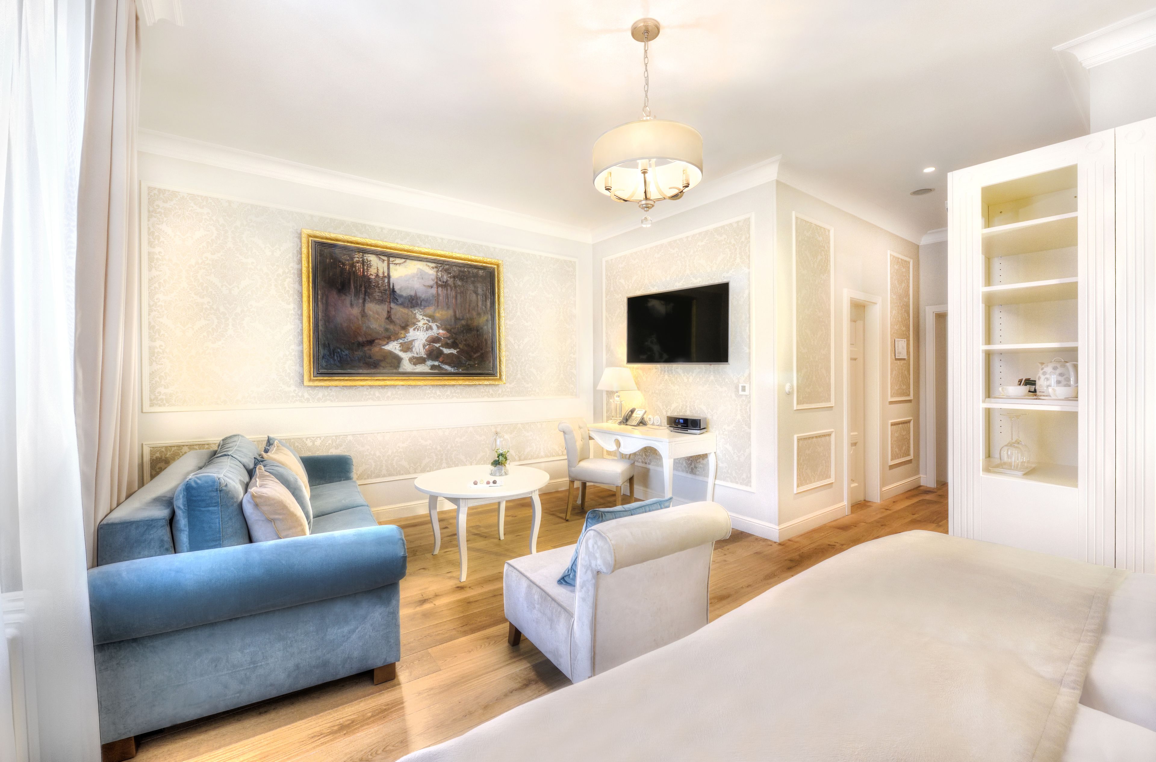 A modern living room with a sofa, armchairs, a coffee table, and a painting on the wall.