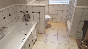 A bathroom with a bathtub, toilet, and a window with blinds. - Pinnacle Point Pool Lodge (Mossel Bay)