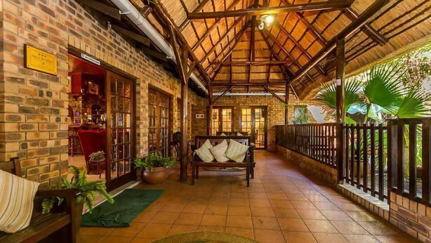 A corridor with a tiled floor, a wooden bench, and potted plants. - La Mer Lodge (Richards Bay)
