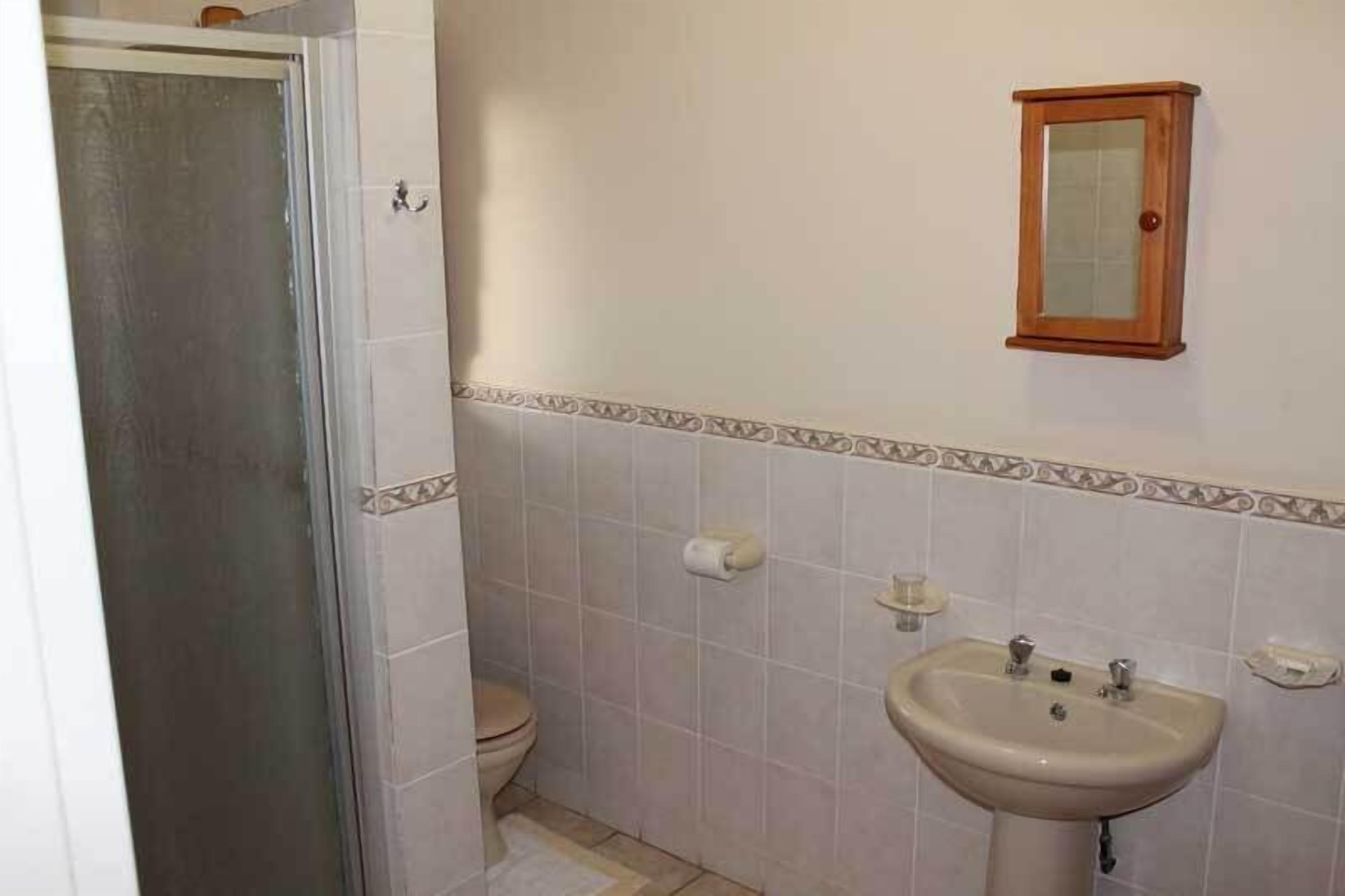 A bathroom with a toilet, sink, and a cabinet.