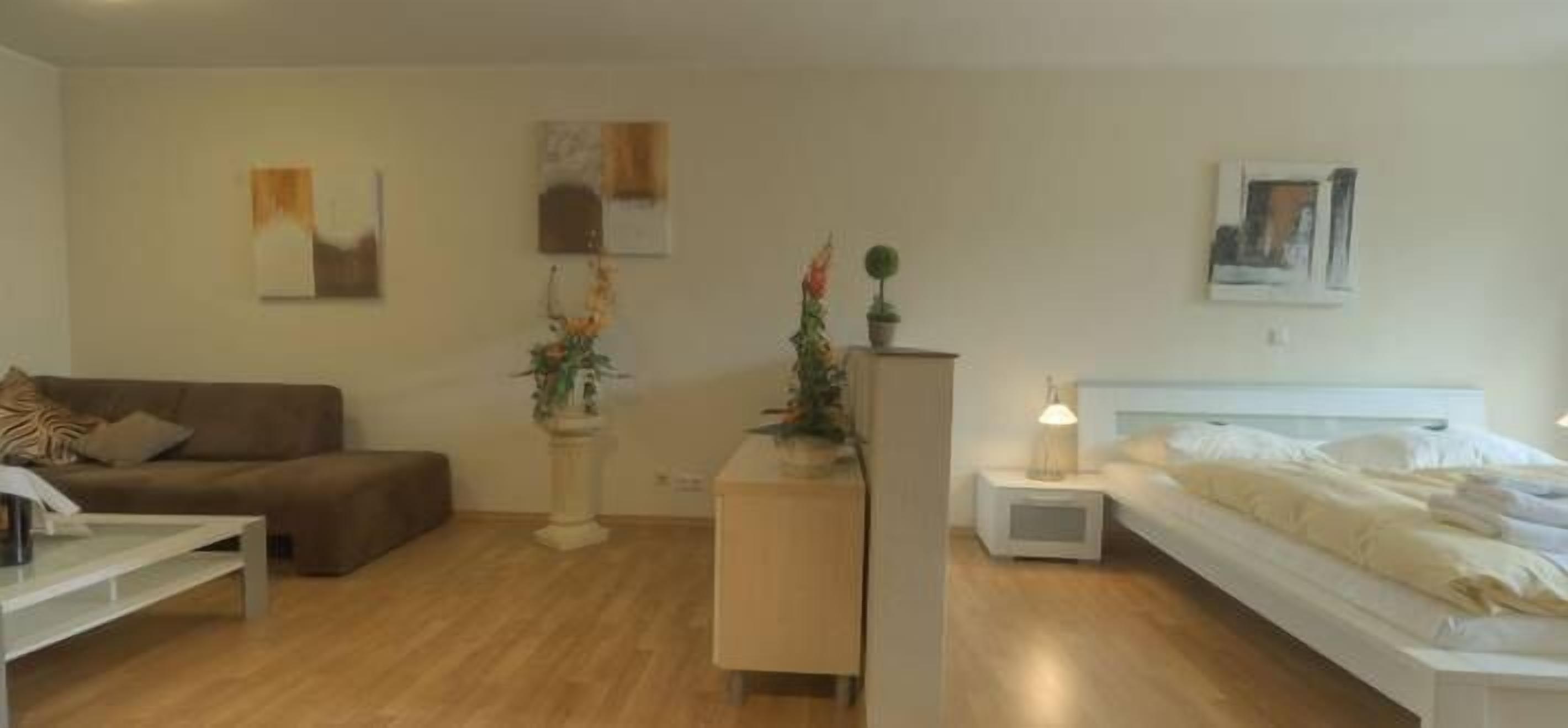 Een moderne slaapkamer met een bed, nachtkastjes, een slaapbank en een salontafel.