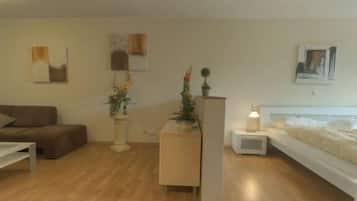 Een moderne slaapkamer met een bed, nachtkastjes, een slaapbank en een salontafel.