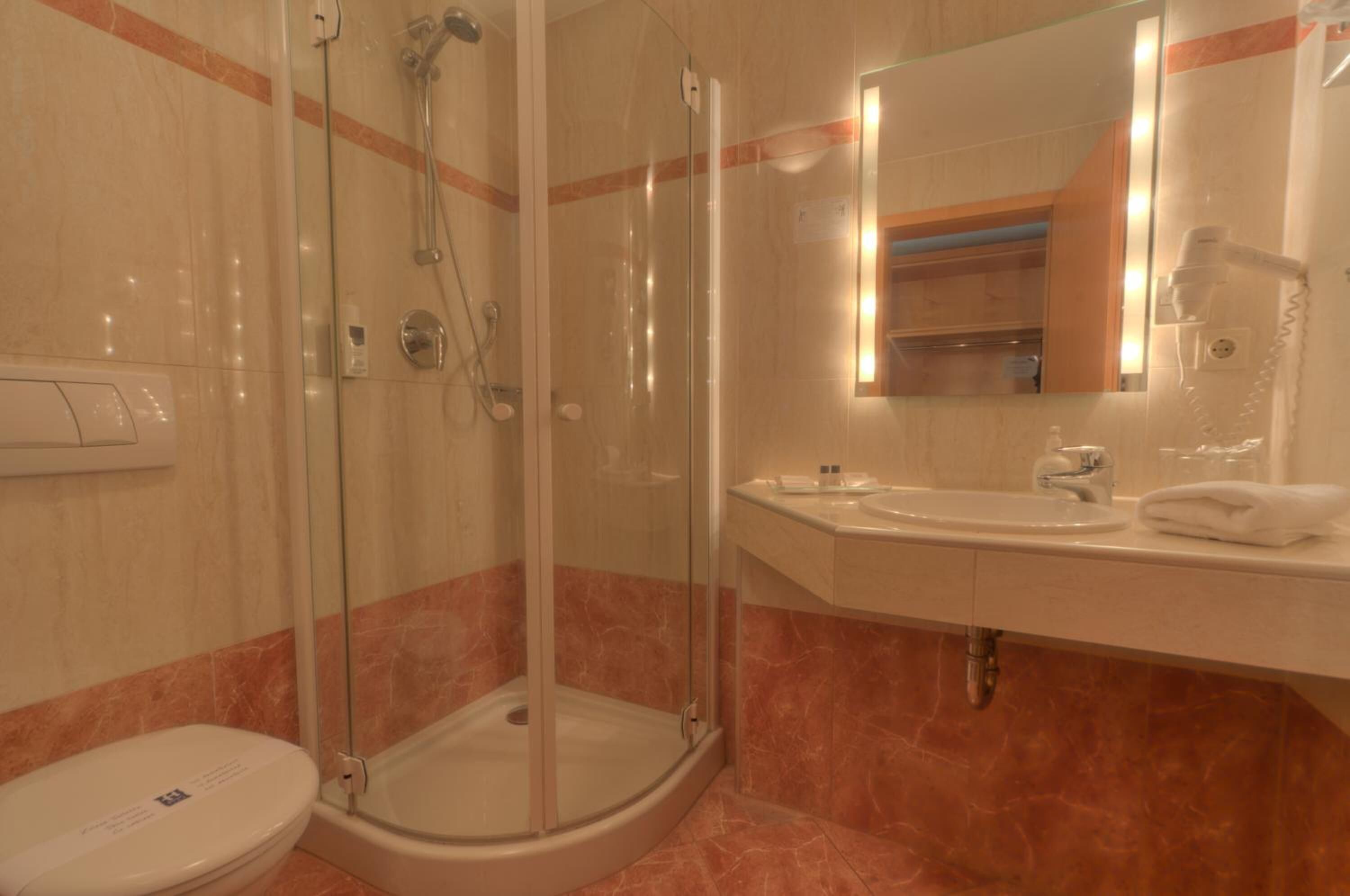 Een badkamer met een douchecabine van glas, een wastafel en een toilet.