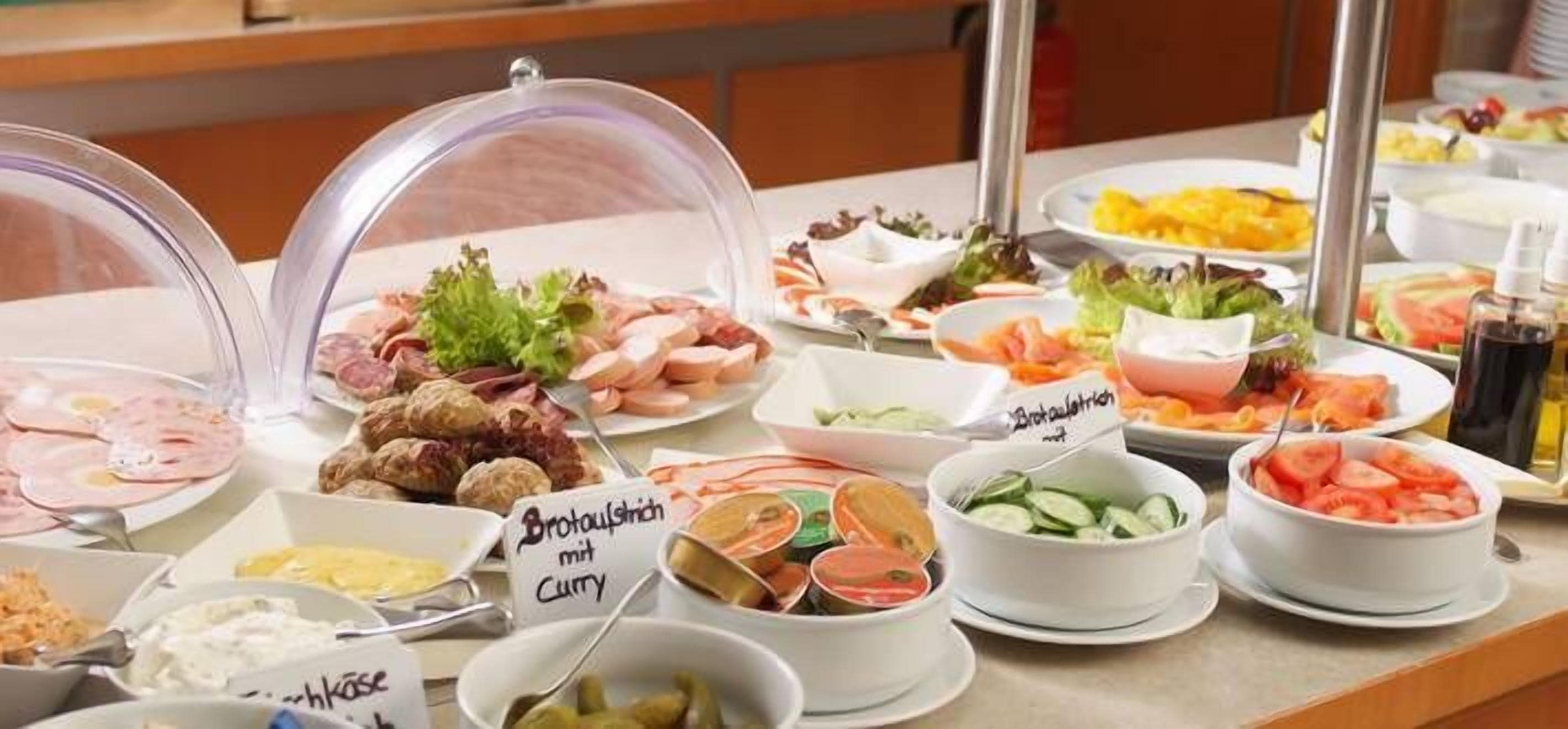 Een buffet met diverse gerechten, waaronder vlees, salades en een bord met de tekst 'Bouillon met Curry'.
