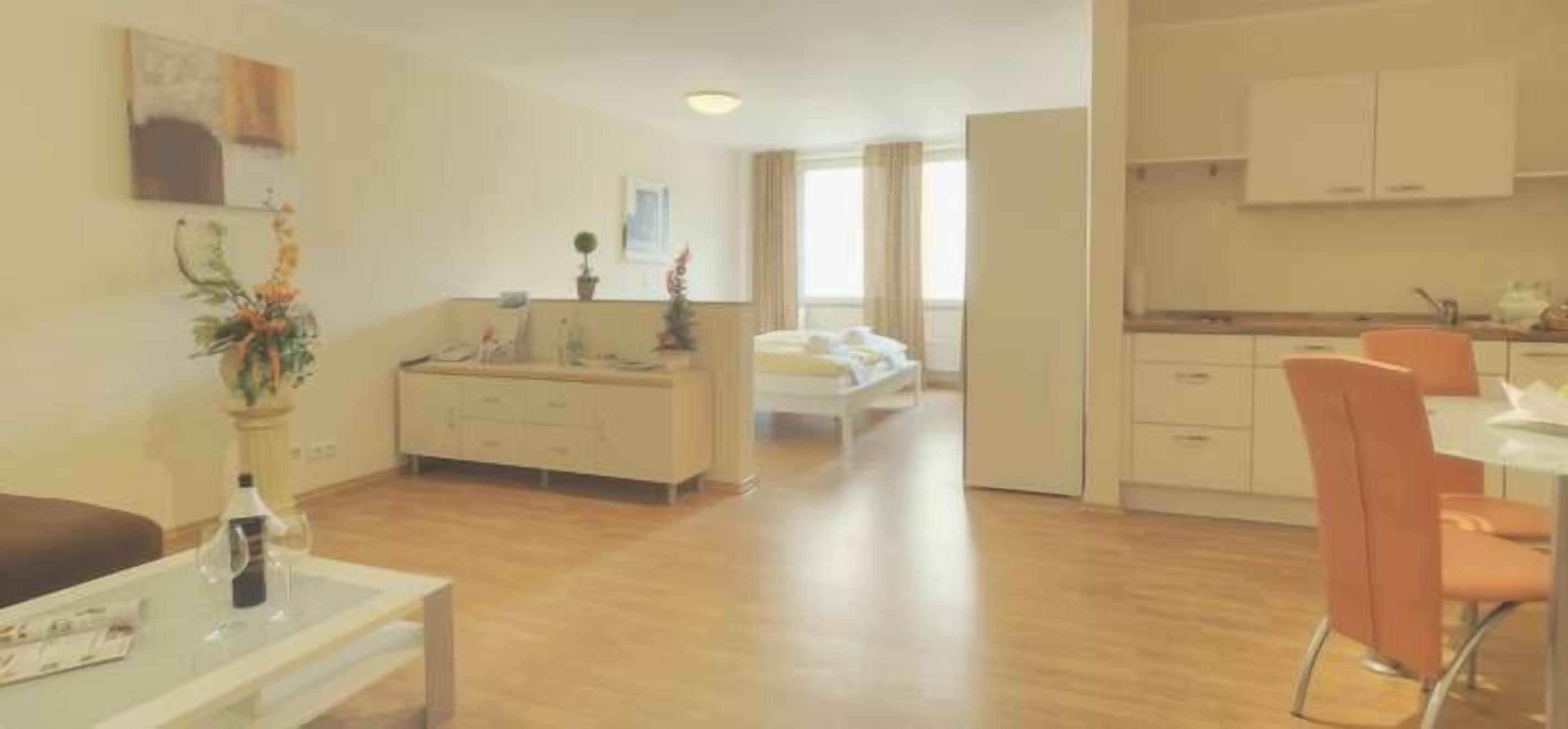 Una habitación de hotel moderna con cama, zona de comedor y kitchenette.