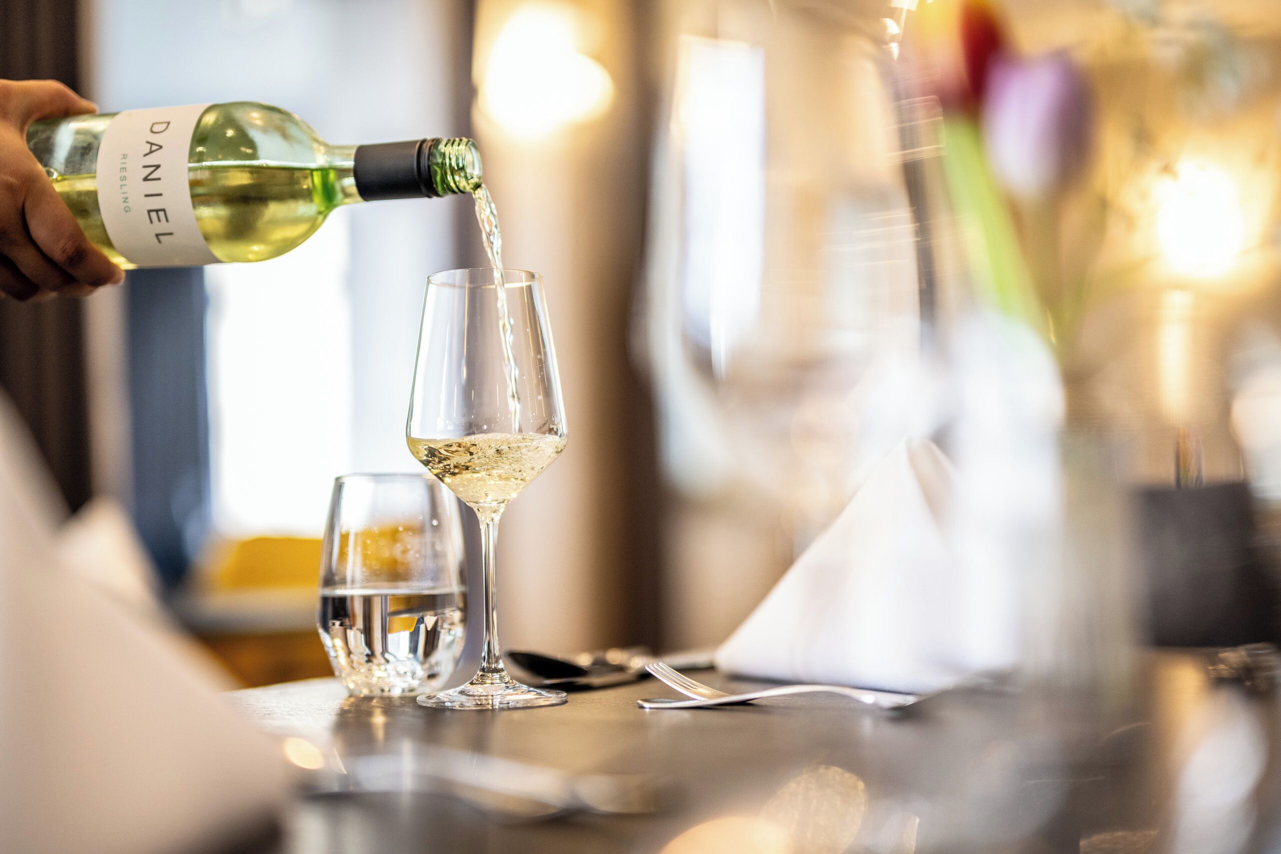 A bottle of wine being poured into a glass.