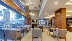 Un restaurante moderno con una combinación de mesas dentro y fuera, con mobiliario contemporáneo y vista a la calle.
