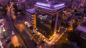 Un hotel moderno con un cartel llamativo, un patio central y vistas a la calle.