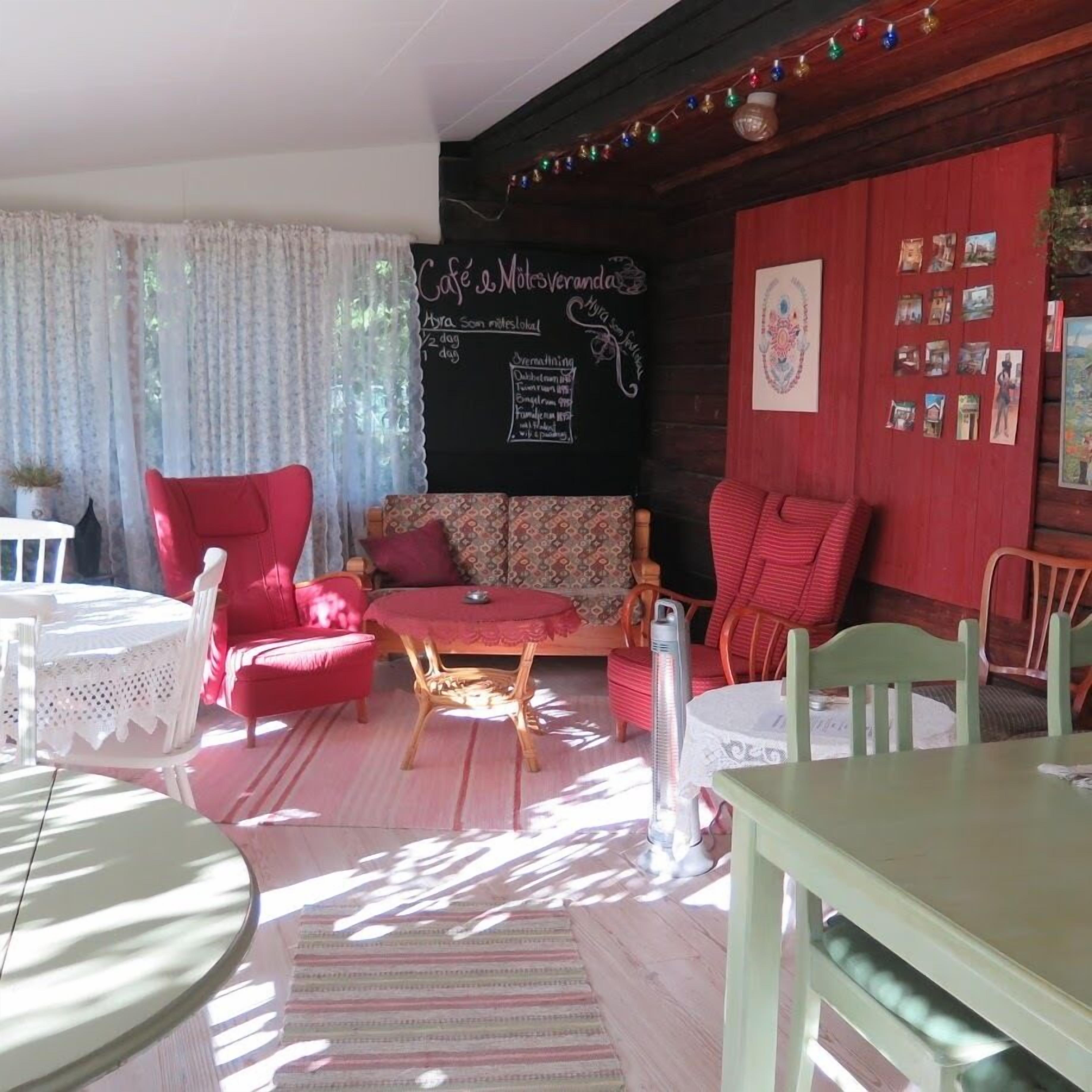 Una habitación acogedora con un sofá rojo, una mesita y una silla. Hay una pizarra con escritura en la pared.