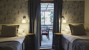 A room with two beds, a bench, and a view through a window. - Woodstock B&B & Studio Apartments (Balsta)