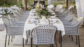 A long dining table set with white tablecloth, surrounded by wicker chairs, on a wooden deck. - Woodstock B&B & Studio Apartments (Balsta)