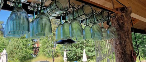 A wooden deck with a hot tub, outdoor furniture, and hanging glass lamps.