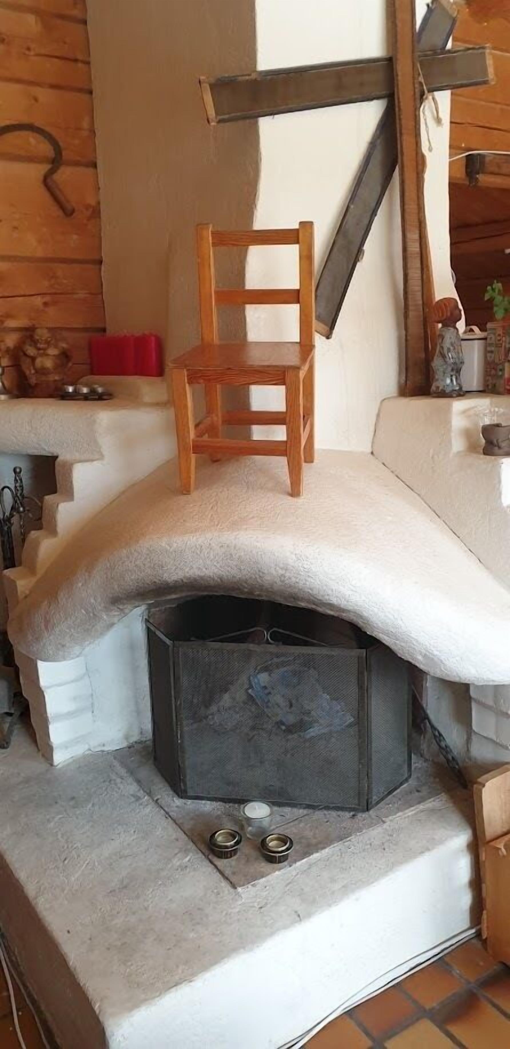 Una habitación acogedora con chimenea, una silla de madera y una escalera.
