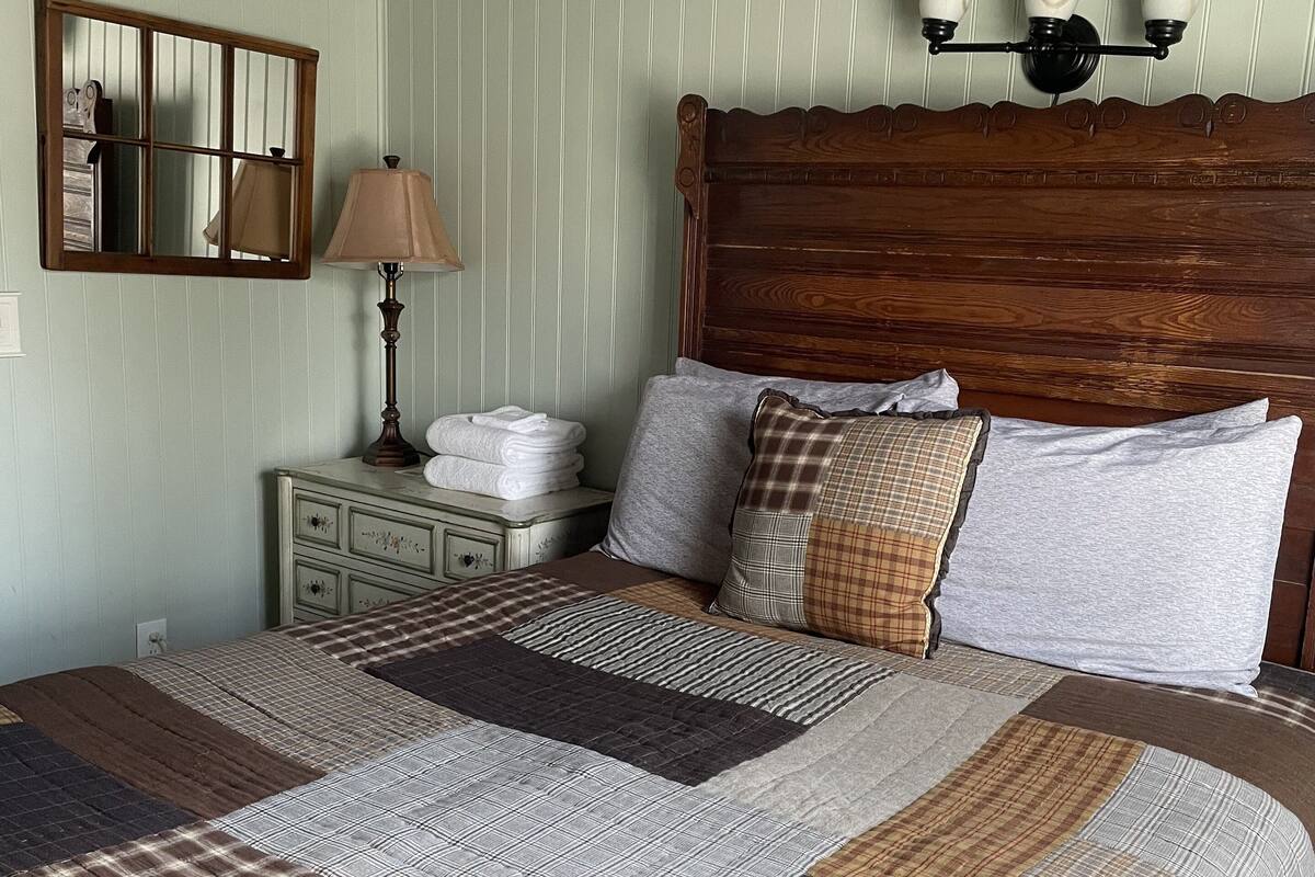 Un dormitorio con una cama grande, una mesita de noche, una lámpara y un aplique de pared.