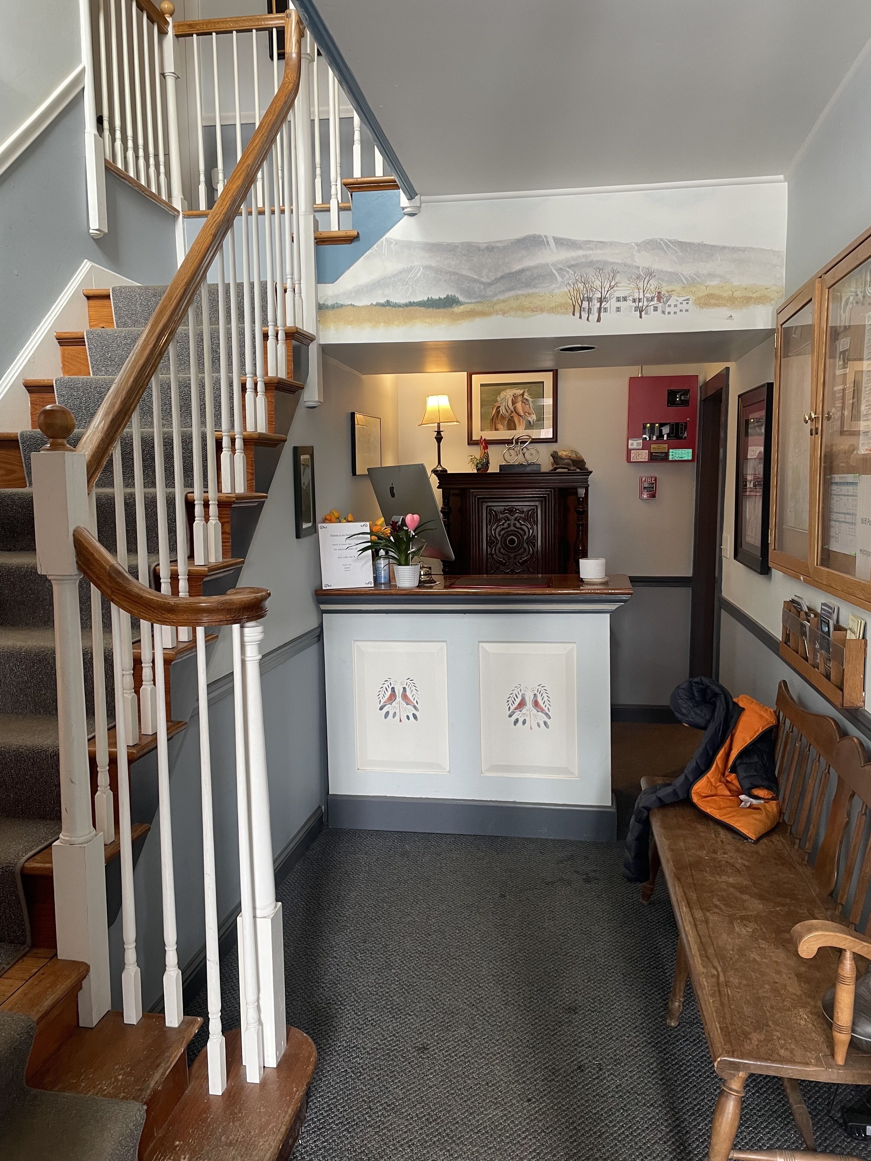 A staircase with wooden balusters, a desk with a lamp, a fire extinguisher, and a bench.