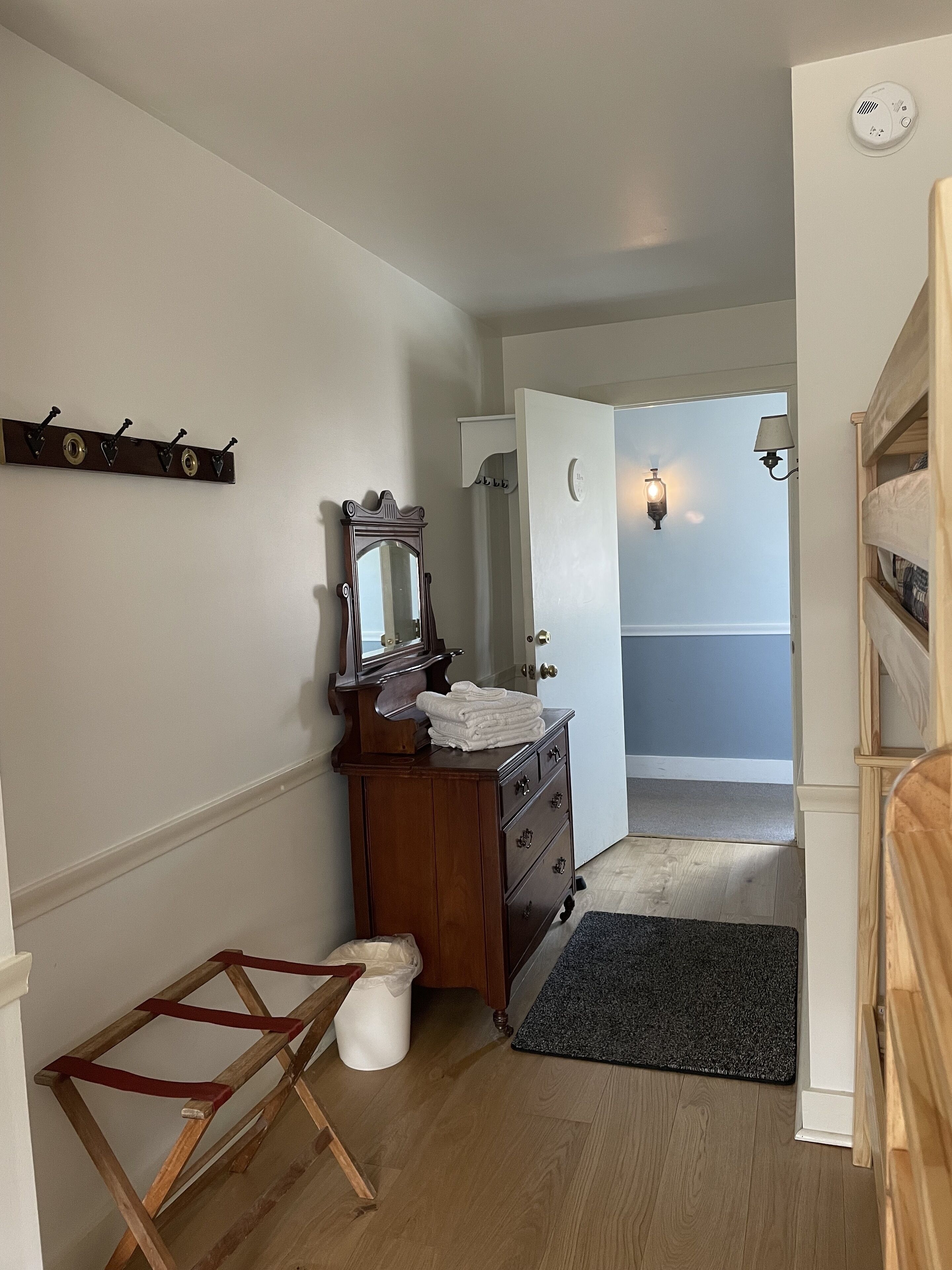 Un couloir avec une commode en bois, un miroir et un porte-manteau.