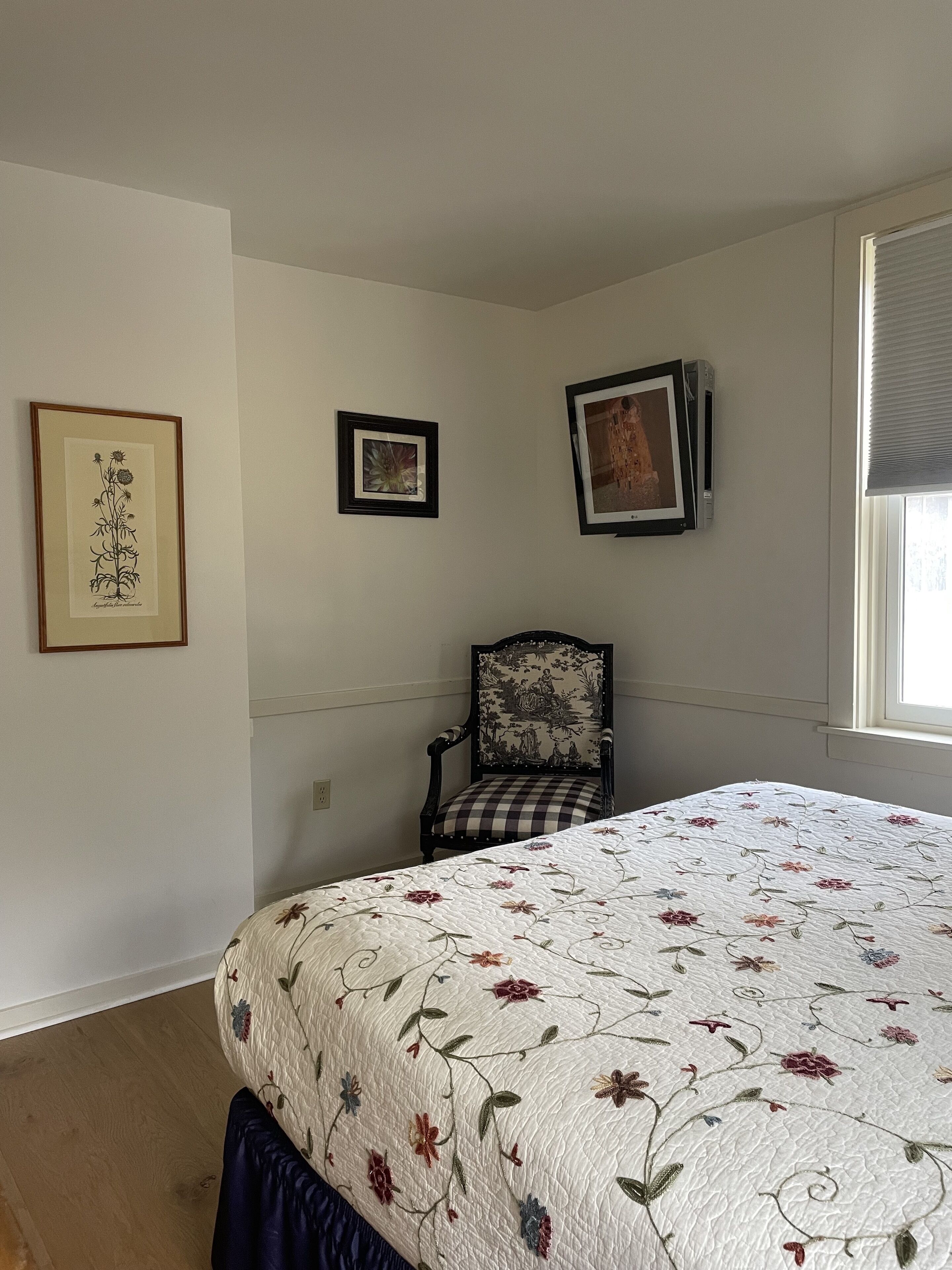 Un dormitorio con una cama, una silla y tres cuadros en la pared.