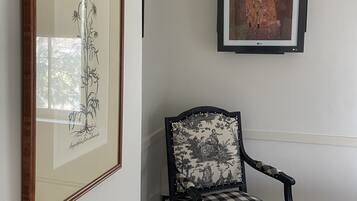 A room with a framed botanical print, a framed artwork, and a checkered armchair.