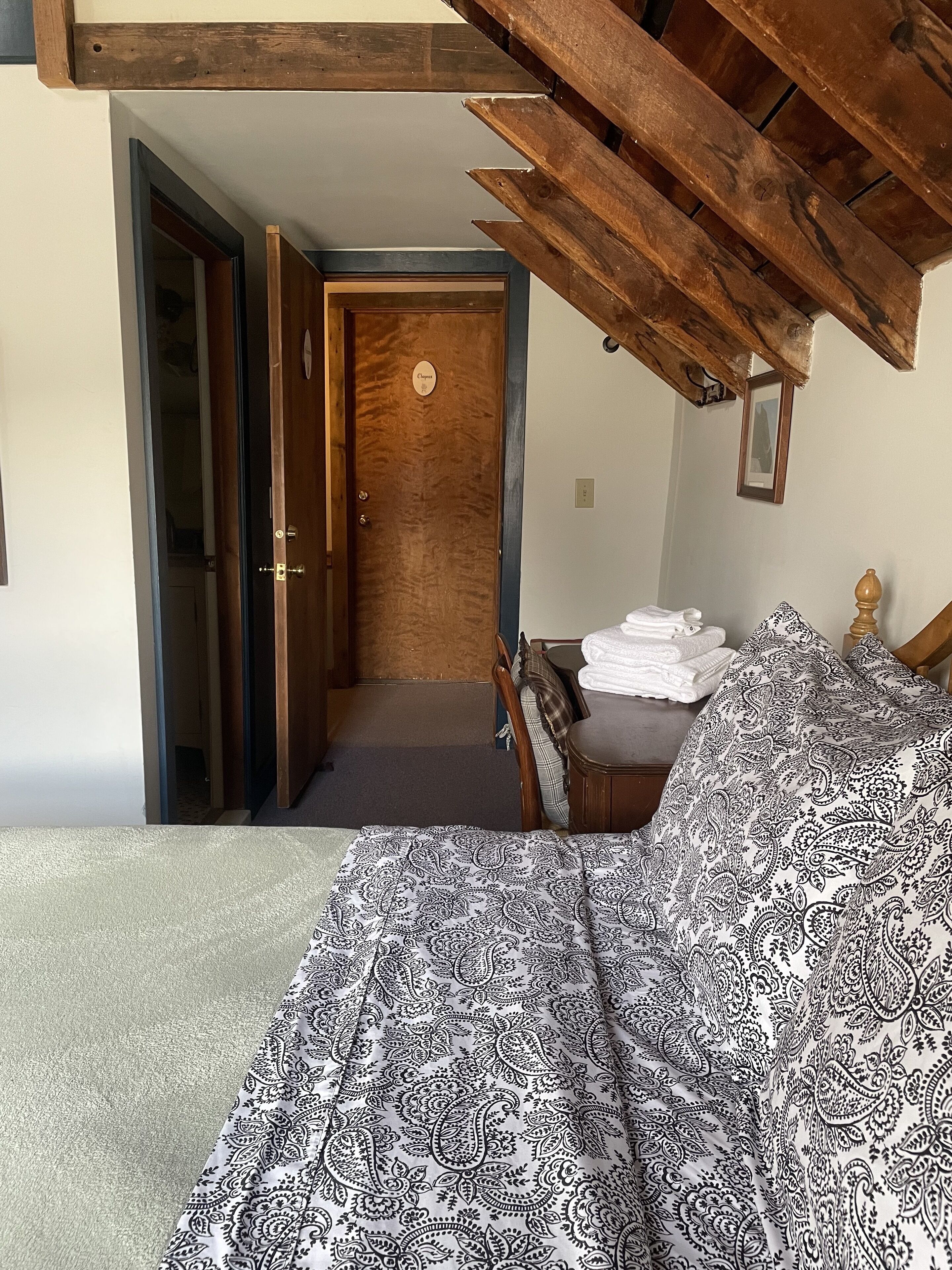 A bedroom with a bed, a wooden door, and a staircase leading to another room.