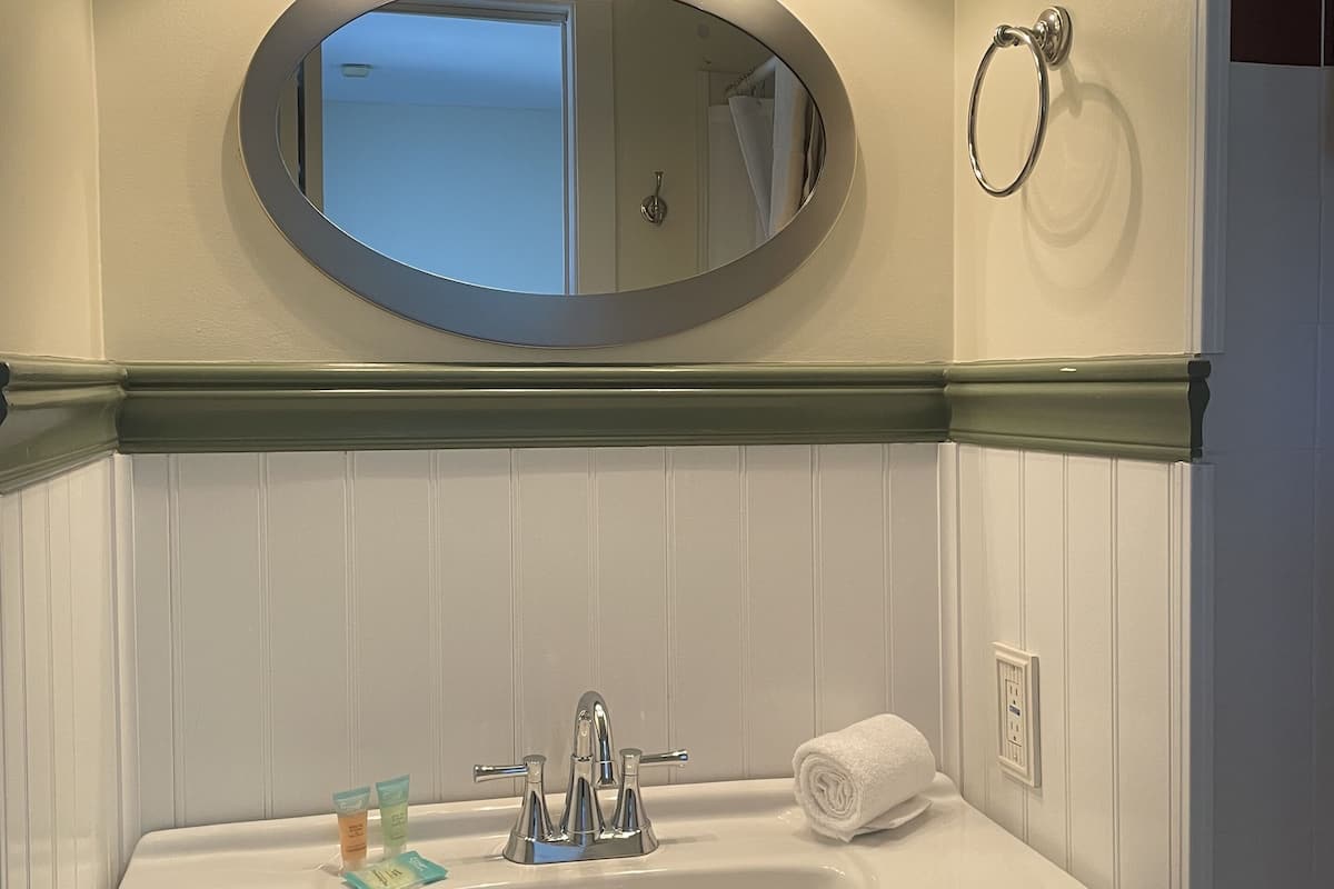 Un baño con un lavamanos blanco, un espejo y tres luces sobre él.