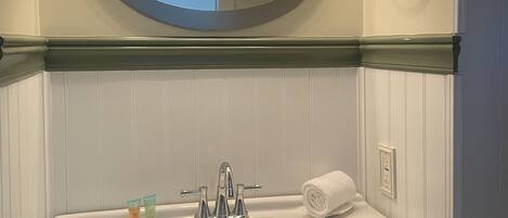 A bathroom with a white sink, a mirror, and three lights above it.