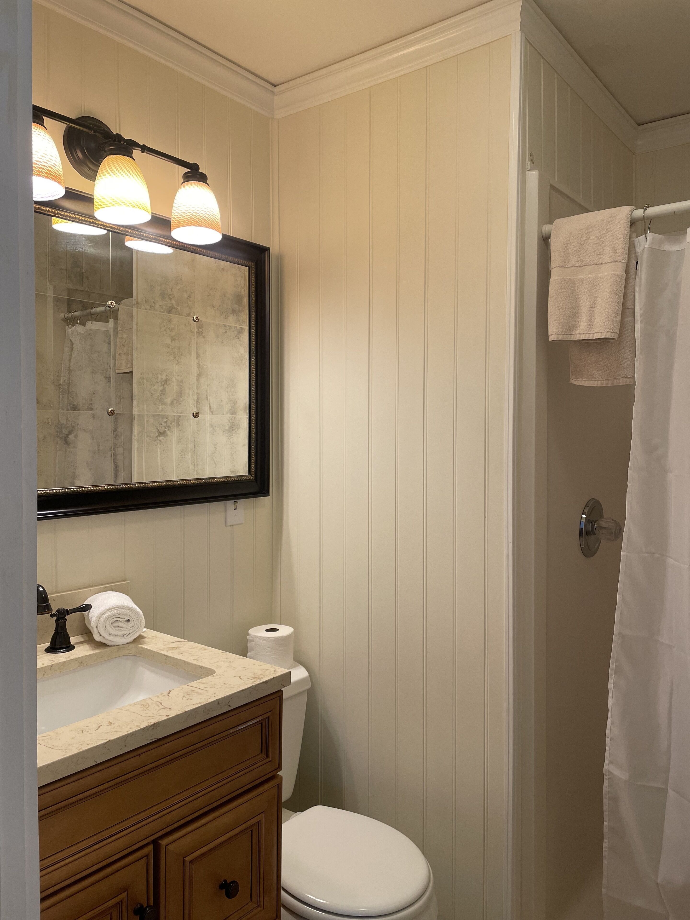 Un baño con tocador, lavabo, espejo e inodoro.