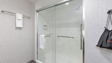 Un baño moderno con cabina de ducha de vidrio, un perchero y un bolso colgado de un gancho.