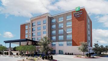 A Holiday Inn Express & Suites building with a modern design, featuring a mix of brick and glass facade, multiple floors, and a covered parking area.