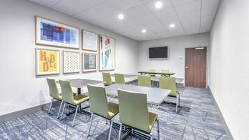 A conference room with a large table, several chairs, and framed artwork on the walls.