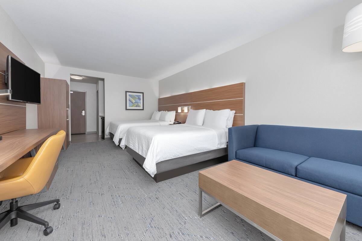 A hotel room with a bed, a sofa, a desk, and a TV.