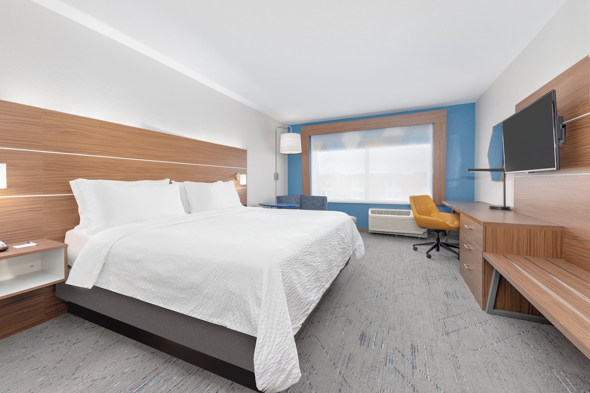 Une chambre d’hôtel moderne équipée d’un grand lit, d’un bureau, d’une chaise et d’une télévision.