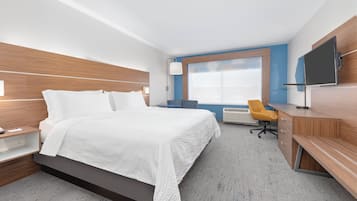 A modern hotel room with a large bed, a desk, a chair, and a TV.