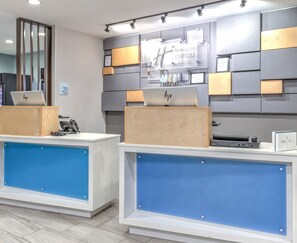A hotel reception desk with a modern design, featuring a check-in counter, a computer, and a sign for Holiday Inn Express & Suites. - Holiday Inn Express & Suites Moore by IHG (Moore)