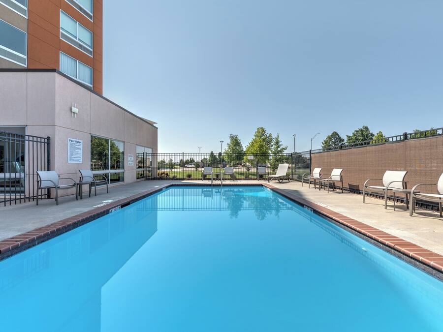 A swimming pool with lounge chairs and a building with a sign that reads "Pool Rules".
